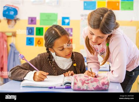 Young girls helping each other in a school classroom Stock Photo - Alamy