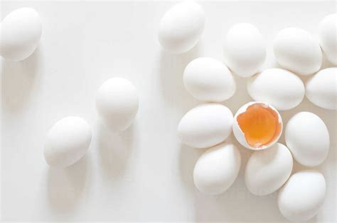 White eggs with egg yolk on white background, close up stock photo