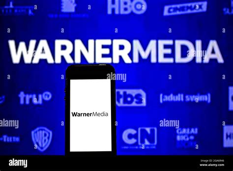 In this photo illustration a WarnerMedia logo seen displayed on a smartphone and in the ...