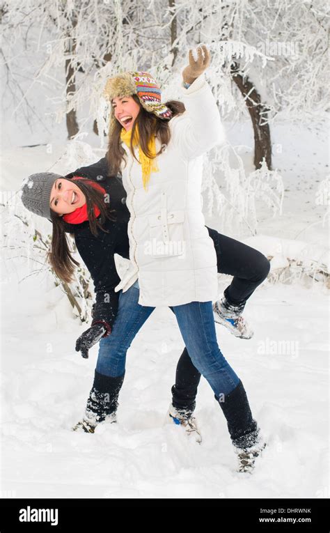 Two young women playing in the snow Stock Photo - Alamy