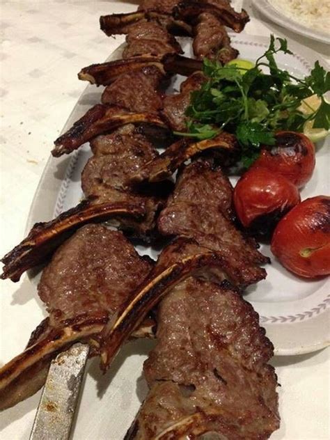 a plate with meat and vegetables on it next to rice, tomatoes and parsley