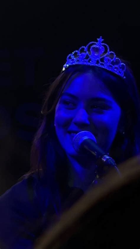 a woman wearing a tiara and singing into a microphone