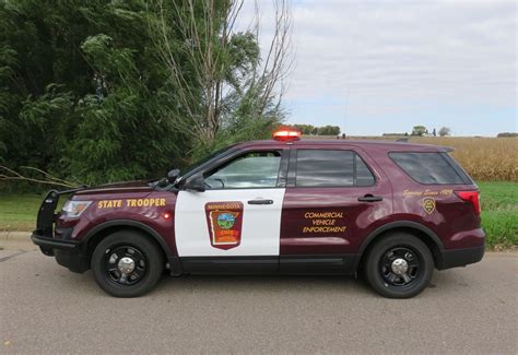 a red and white police car parked on the side of the road in front of some trees