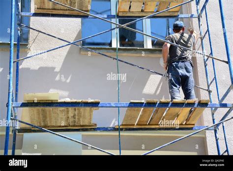 Painting of a stucco exterior wall of a house. A building contractor on ...