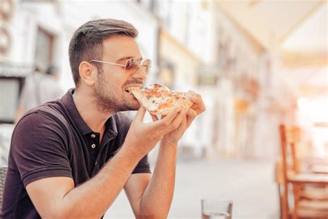 Premium Photo | Young man eating a slice of pizza