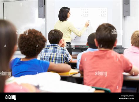 Teacher Standing In Class Using Interactive Whiteboard Stock Photo - Alamy