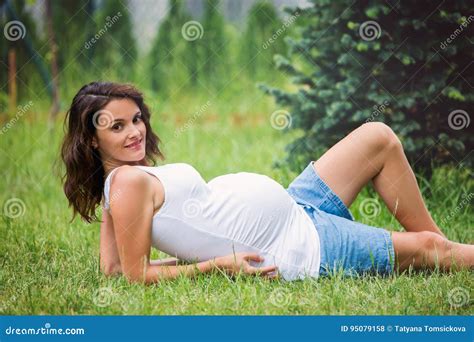 Beautiful Young Pregnant Woman, Lying Down in the Grass, Making Stock ...