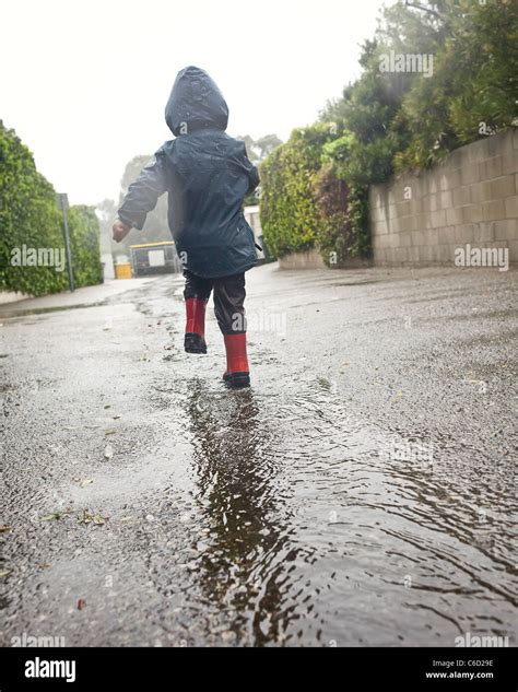 Caucasian boy walking in rain puddle Stock Photo - Alamy