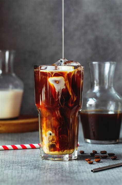 Cream pouring into glass with iced coffee on table · Free Stock Photo