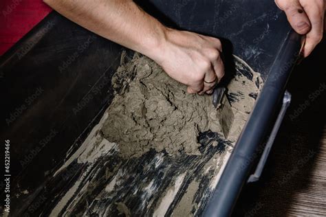 A person mixes cement and water in a container to get the finished ...