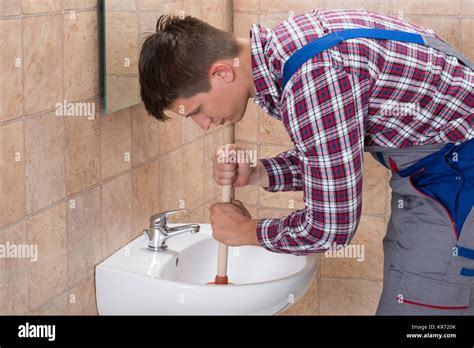 Plumber Using Plunger In Bathroom Sink Stock Photo - Alamy