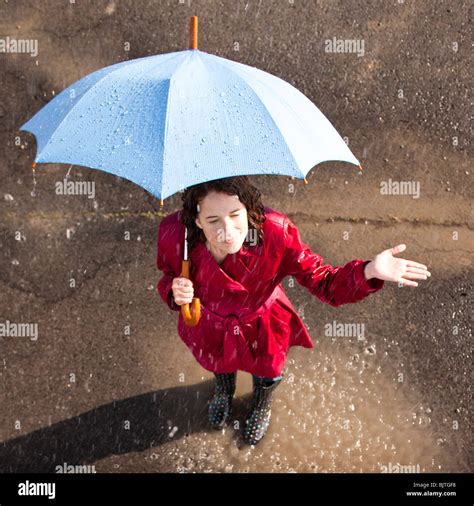 Young woman standing in rain holding umbrella Stock Photo - Alamy