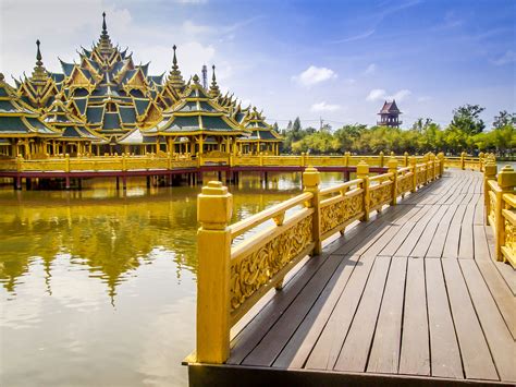 a wooden bridge over water leading to a building with many spires in ...