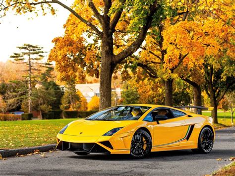 a yellow sports car is parked on the side of the road in front of some ...