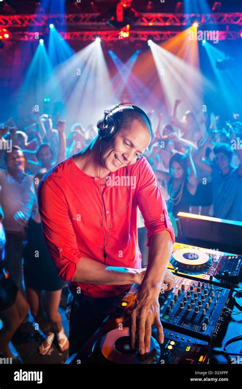 DJ at turntable with crowd on dance floor in background Stock Photo - Alamy