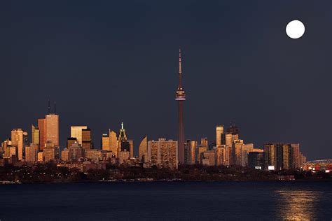 Red sunset glow on Toronto skyline with bright rising supermoon ...