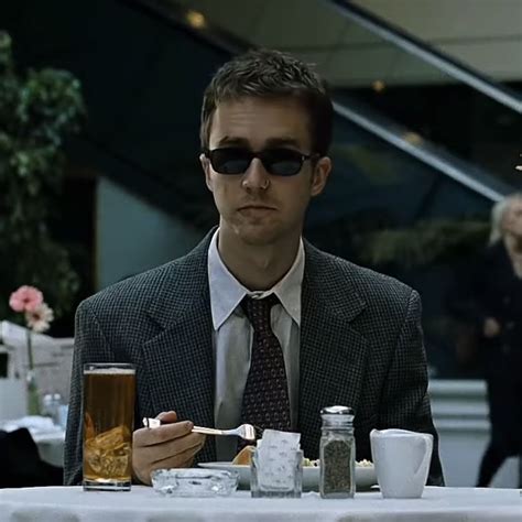 a man sitting at a table with food and drinks in front of him, wearing sunglasses