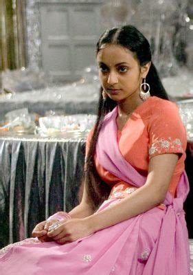 a woman sitting on top of a table wearing a pink sari and silver earrings