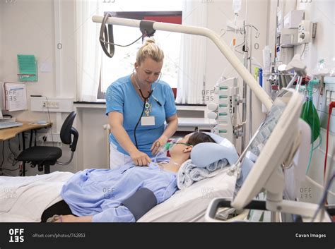 Female doctor examining patient lying on bed in hospital stock photo - OFFSET