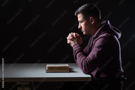 Christian prayer. Man praying before bible. Guy crossed his palms for ...