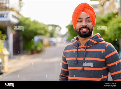 Happy Indian Sikh man smiling outdoors and wearing orange turban Stock ...