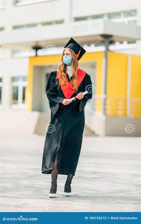 A Graduate Student in a Medical Mask, in a Black Graduation Dress, with ...