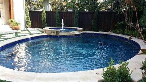 Classic oval shaped swimming pool with attached spa featuring natural ...