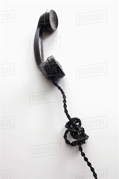 An old-fashioned telephone cord tangled in a knot - Stock Photo - Dissolve