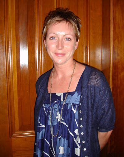 a woman standing in front of wooden paneled walls with a necklace on her neck