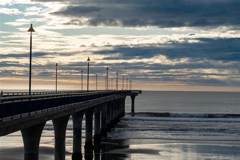 A long pier with a lighthouse and a beach · Free Stock Photo