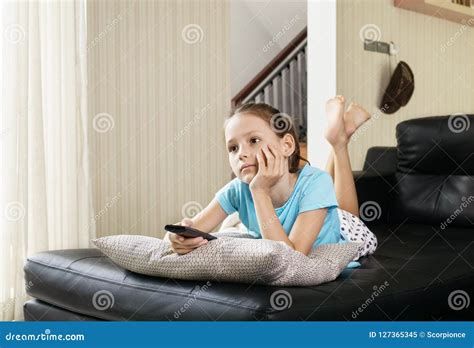 Cute Preteen Girl Watching TV on Couch Using Remote Control. Living Room Interior in Background ...