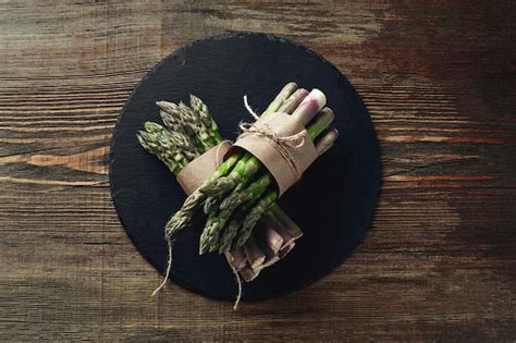 Premium Photo | An edible raw stems of asparagus on a wooden background