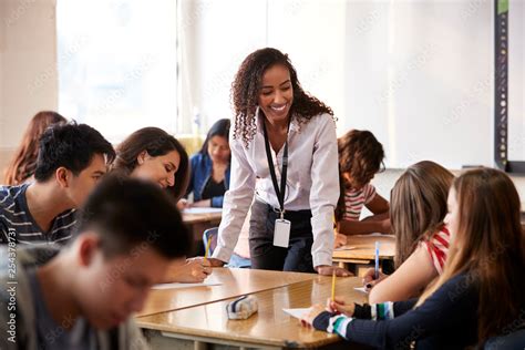 Female High School Teacher Standing By Student Table Teaching Lesson Stock Photo | Adobe Stock