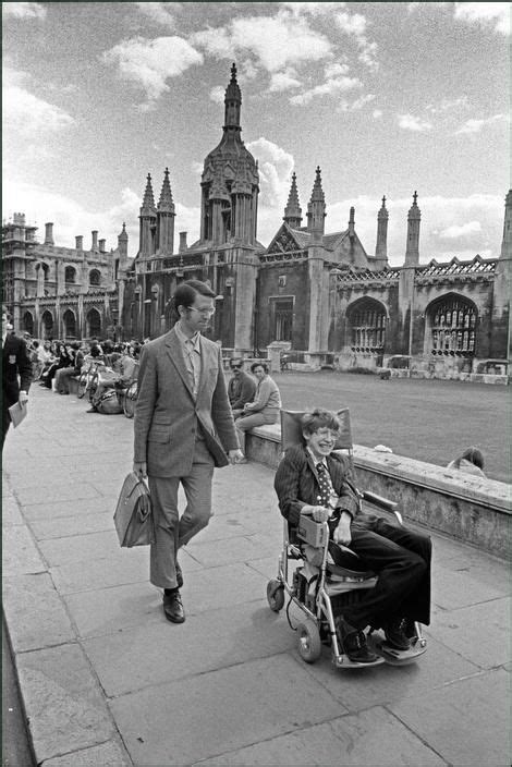 Professor Stephen Hawking in his wheelchair in front of university buildings, Cambridge. 1977 ...