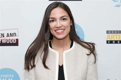 Download Alexandria Ocasio-cortez Smiling By White Backdrop Wallpaper | Wallpapers.com