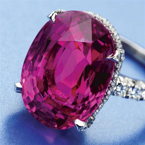 PINK SAPPHIRE AND DIAMOND RING The oval sapphire weighing 17.16 carats, bordered by numerous ...