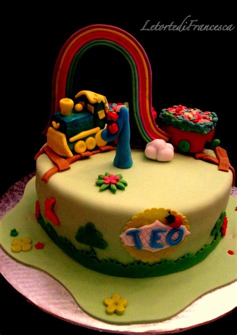 a birthday cake decorated with a train and rainbow