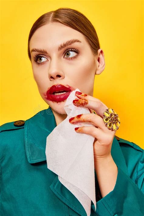 Young Woman in Green Coat with Smudged Red Lipstick Wiping Mouth after Eating Nuggets Over ...