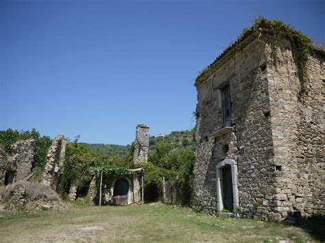 an old stone building sitting on top of a lush green field next to a forest