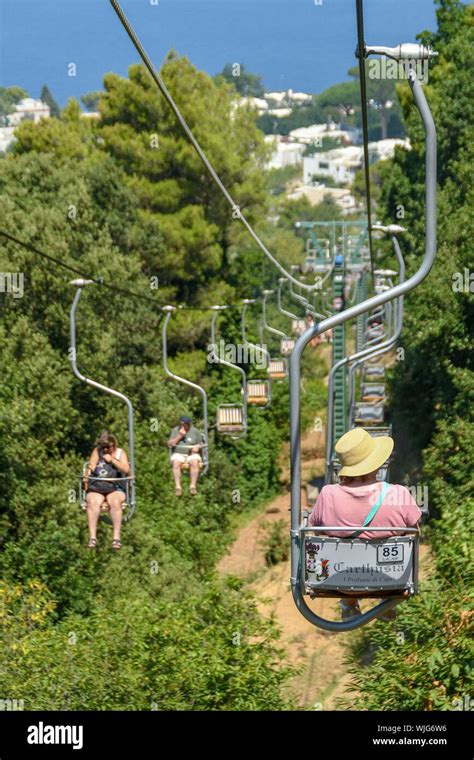 ANACAPRI, ISLE OF CAPRI, ITALY - AUGUST 2019: Visitors on a chair lift travelling up and down to ...