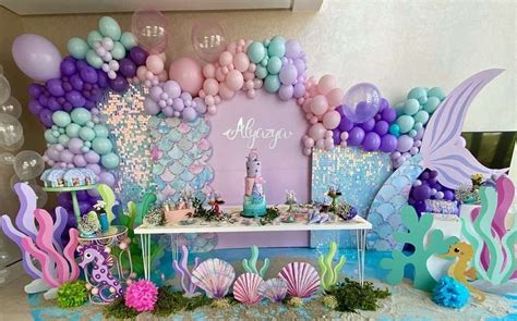 an under the sea themed birthday party with balloons, decorations and mermaid tail cake toppers