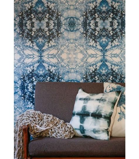 a brown couch sitting in front of a wall covered in blue and white ...