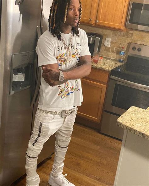 a man with dreadlocks standing in front of a stainless steel refrigerator freezer