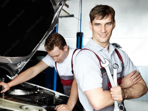 Motor mechanics fixing the engine of a car in a garage Stock Photo | Adobe Stock