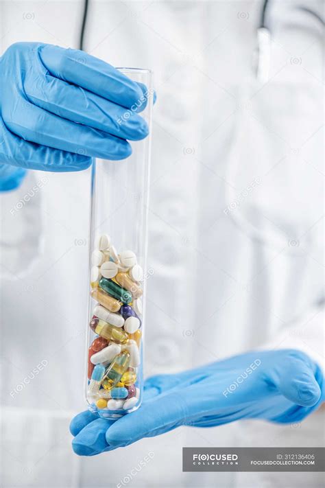 Pharmaceutical scientist hands holding laboratory glass filled with colorful pills. — healthcare ...