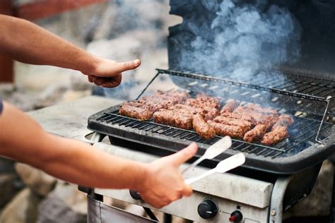 Premium Photo | Man cooking romanian mititei on grill