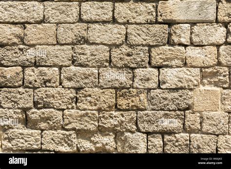 Masonry wall of old stone blocks of limestone. Background texture of ...