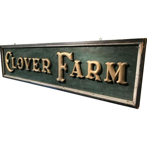 A wonderful wooden advertising sign with carved gilt letters on a green sand painted background ...