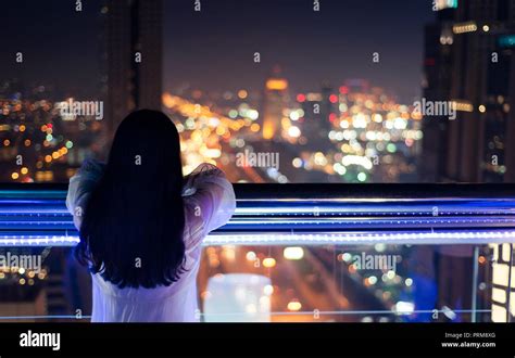 Woman enjoying with night city view from the balcony Stock Photo - Alamy