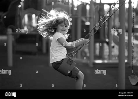 Child swinging on the playground. Child playing on the playground in kindergarten. Joyful kid on ...